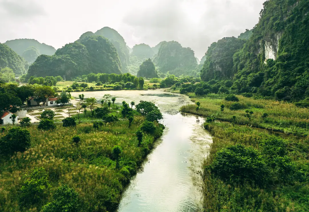 Voyage en Asie – La rivière Ngô Đồng serpente entre les pics karstiques et la végétation à Tam Cốc dans la région de Ninh Binh au Vietnam.