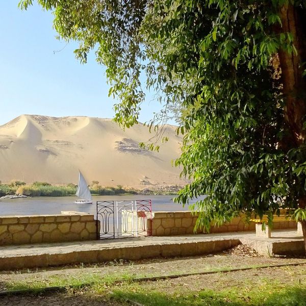 Dune de sable doré surplombant le Nil avec un voilier blanc
