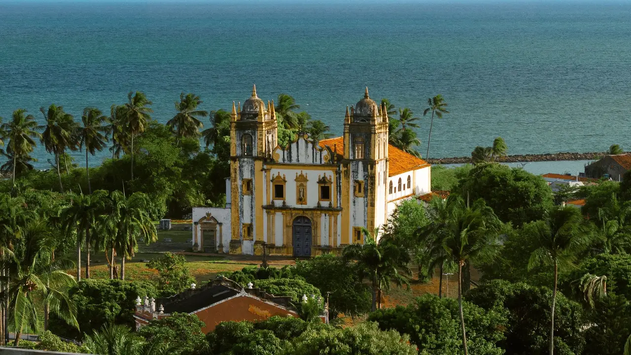 Voyage au Brésil – Église coloniale baroque d'Olinda entourée de palmiers verdoyants avec vue sur l'océan Atlantique dans l'État du Pernambouc.