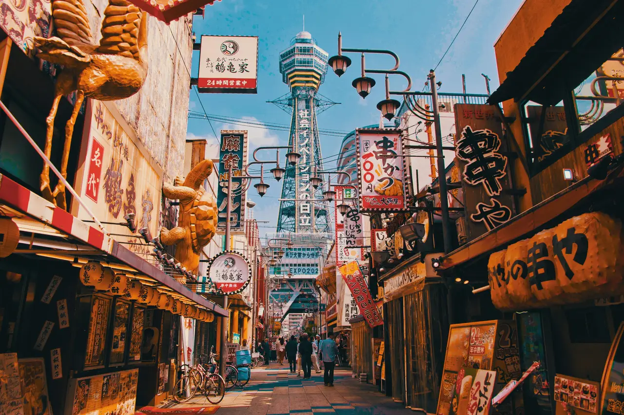 Voyage en Asie – Ruelle animée aux enseignes colorées et lumineuses dans le quartier rétro de Shinsekai avec la tour Tsutenkaku en arrière-plan à Osaka au Japon.