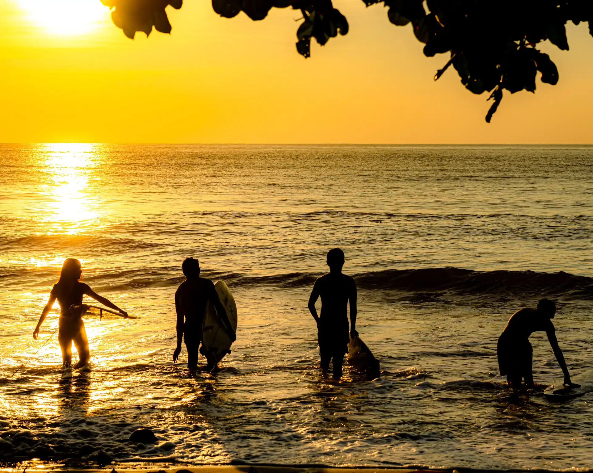 Silhouettes de surfeurs au bord de la mer au coucher du soleil sur une plage des Philippines.