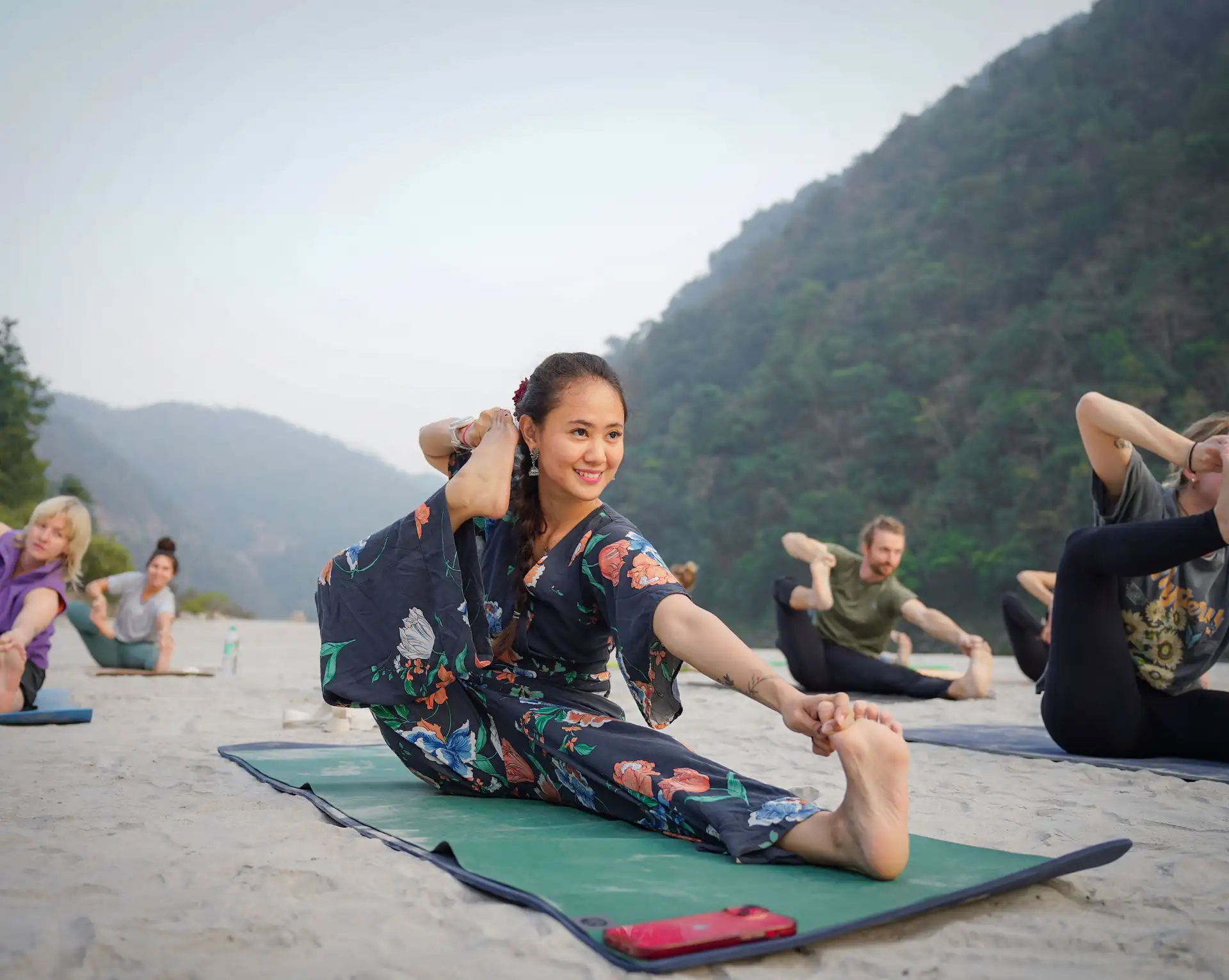 Groupe de personnes pratiquant une posture de yoga en plein air entouré par une nature verdoyante au Sri Lanka.