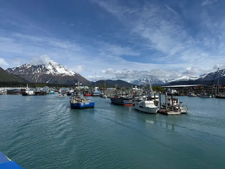 Bateaux de pêche amarrés dans le port de Seward devant les eaux calmes et les montagnes aux sommets enneigés de la péninsule de Kenai