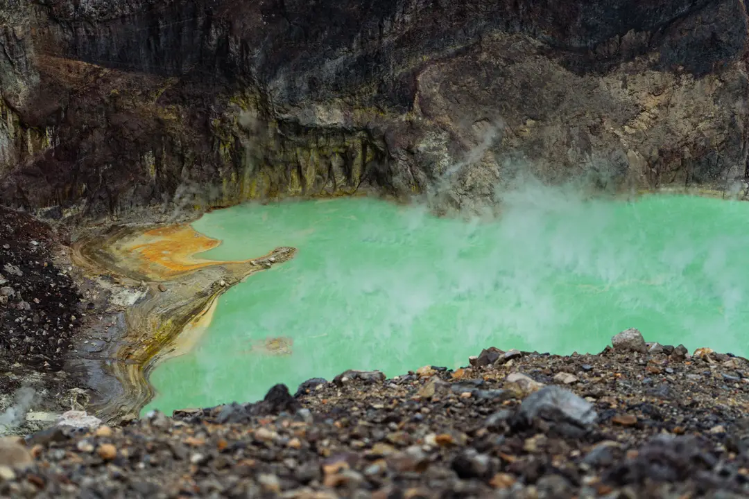 Voyage en Indonésie – Vue plongeante sur le lac de cratère soufré et turquoise du mont Sibayak, un volcan actif près de Berastagi à Sumatra.