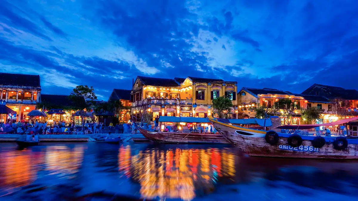 Voyage au Vietnam — Scène nocturne du Vieux Quartier de Hôi An avec lanternes colorées, maisons anciennes et reflets lumineux sur la rivière Thu Bồn.