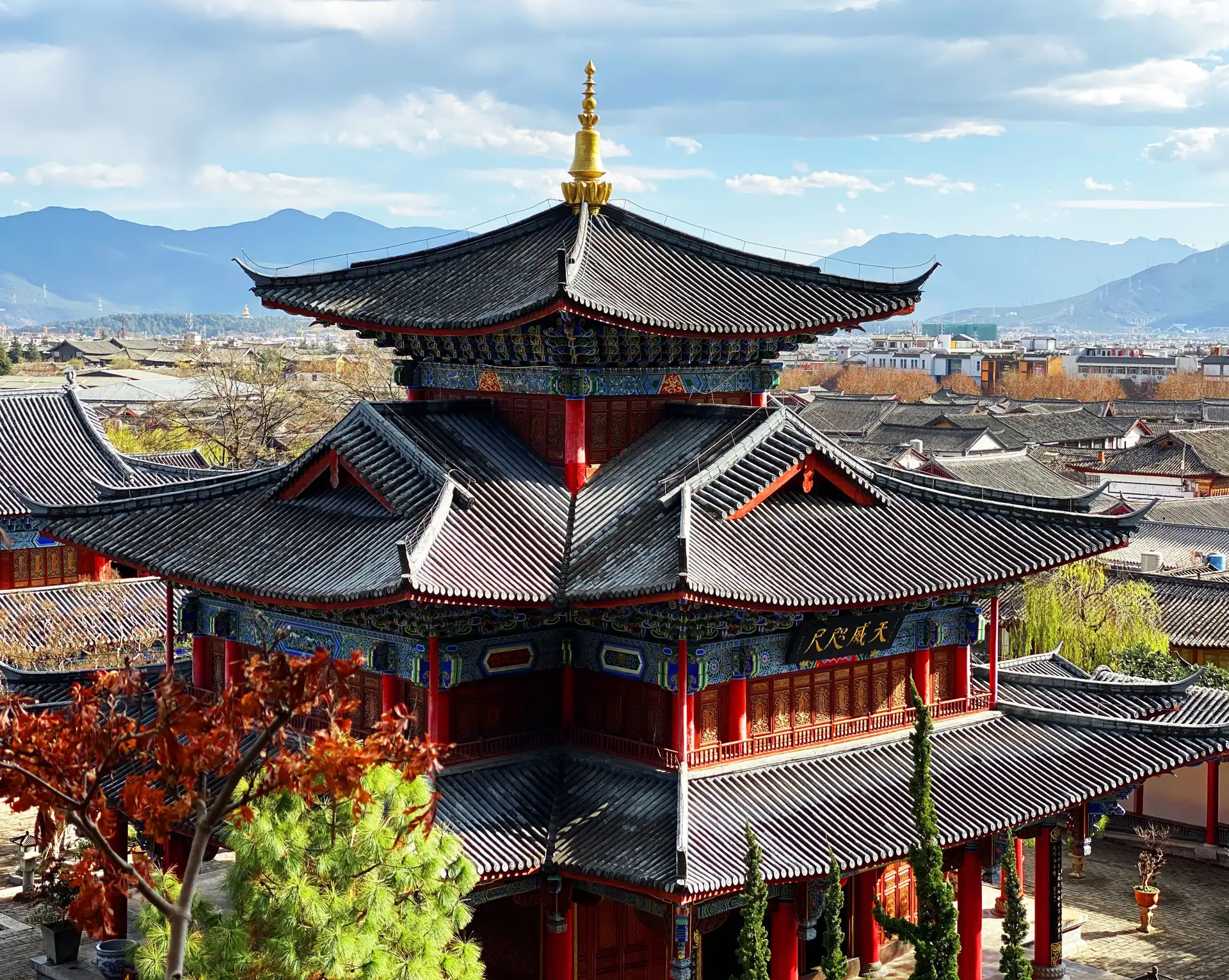 Toit traditionnel d'un temple chinois en bois avec panorama sur les montagnes du Sichuan en arrière-plan.