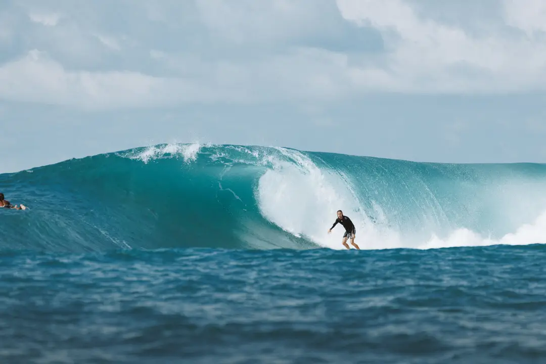 Surfeur en pleine session sur une grande vague turquoise à Uluwatu, Bali