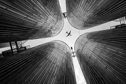 Travel in Asia - Low-angle perspective looking up at four large pillars, arranged to frame a single airplane flying overhead