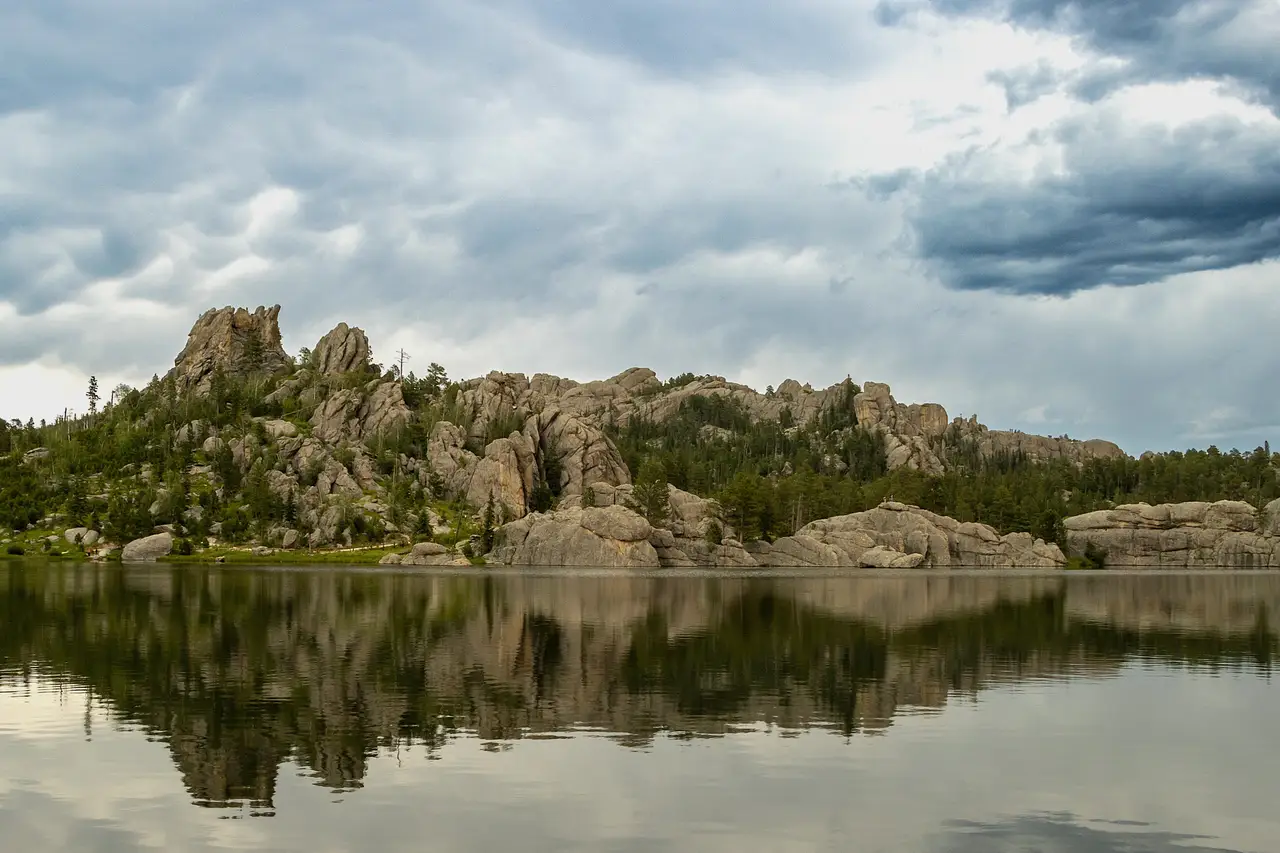 Formations rocheuses granitiques et pins se reflétant dans les eaux calmes de Sylvan Lake au parc d'État de Custer dans les Black Hills