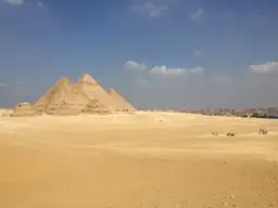 Les grandes pyramides de Gizeh dressées dans le désert sous un ciel bleu en Égypte.