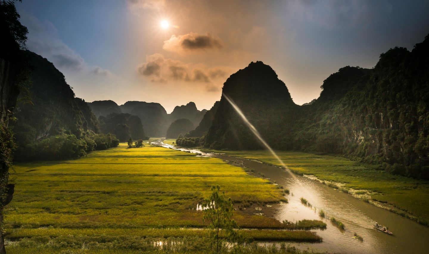 Voyage au Vietnam — Paysage de rizières et formations karstiques dans le Nord Vietnam sous une lumière dorée.
