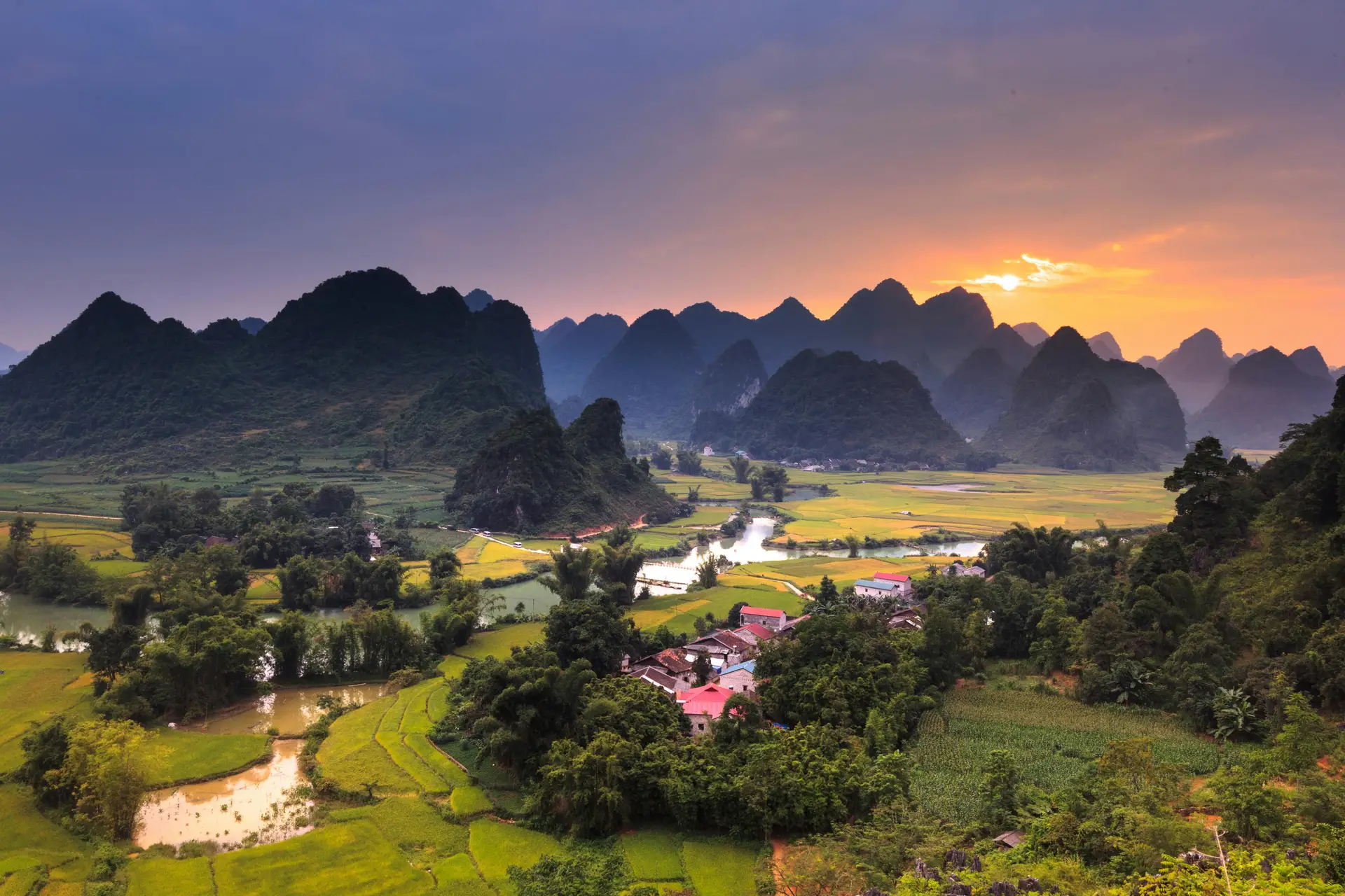 Jonque traditionnelle naviguant entre les pitons karstiques de la baie d'Along sous un ciel dégagé au Vietnam.