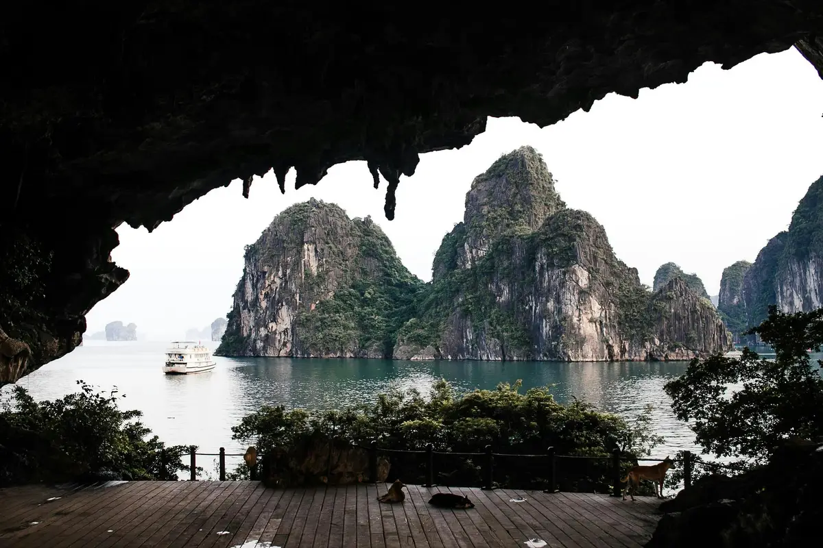 Voyage au Vietnam — Vue de la Baie d’Ha Long depuis l’intérieur d’une grotte avec stalactites et bateau dans l’eau.