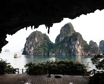 Voyage au Vietnam — Vue de la Baie d’Ha Long depuis l’intérieur d’une grotte avec stalactites et bateau dans l’eau.