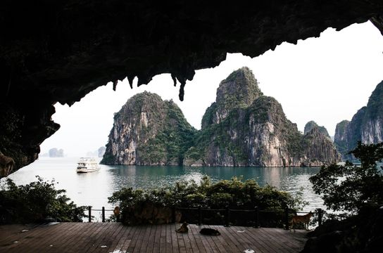 Voyage au Vietnam — Vue de la Baie d’Ha Long depuis l’intérieur d’une grotte avec stalactites et bateau dans l’eau.