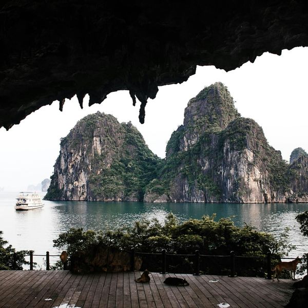 Voyage au Vietnam — Vue de la Baie d’Ha Long depuis l’intérieur d’une grotte avec stalactites et bateau dans l’eau.