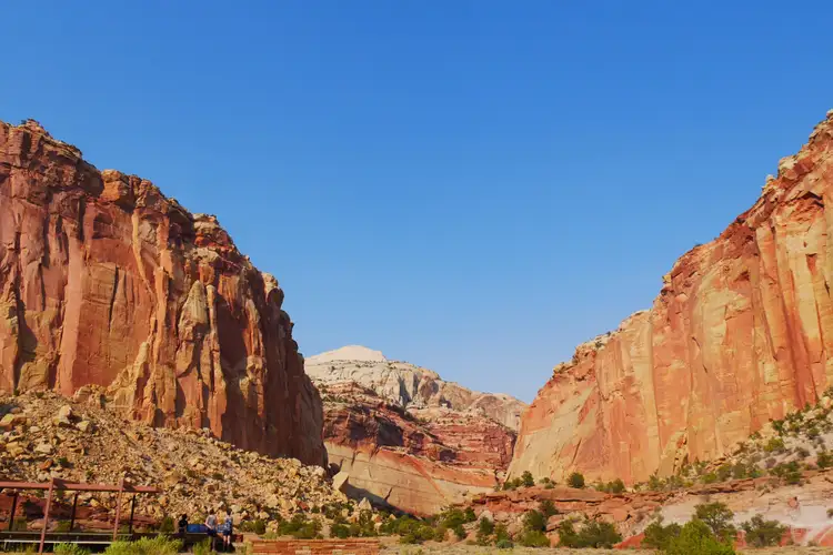 Imposantes falaises rocheuses ocres et rouges de Capitol Reef encadrant un canyon sous un ciel bleu dégagé près de Torrey
