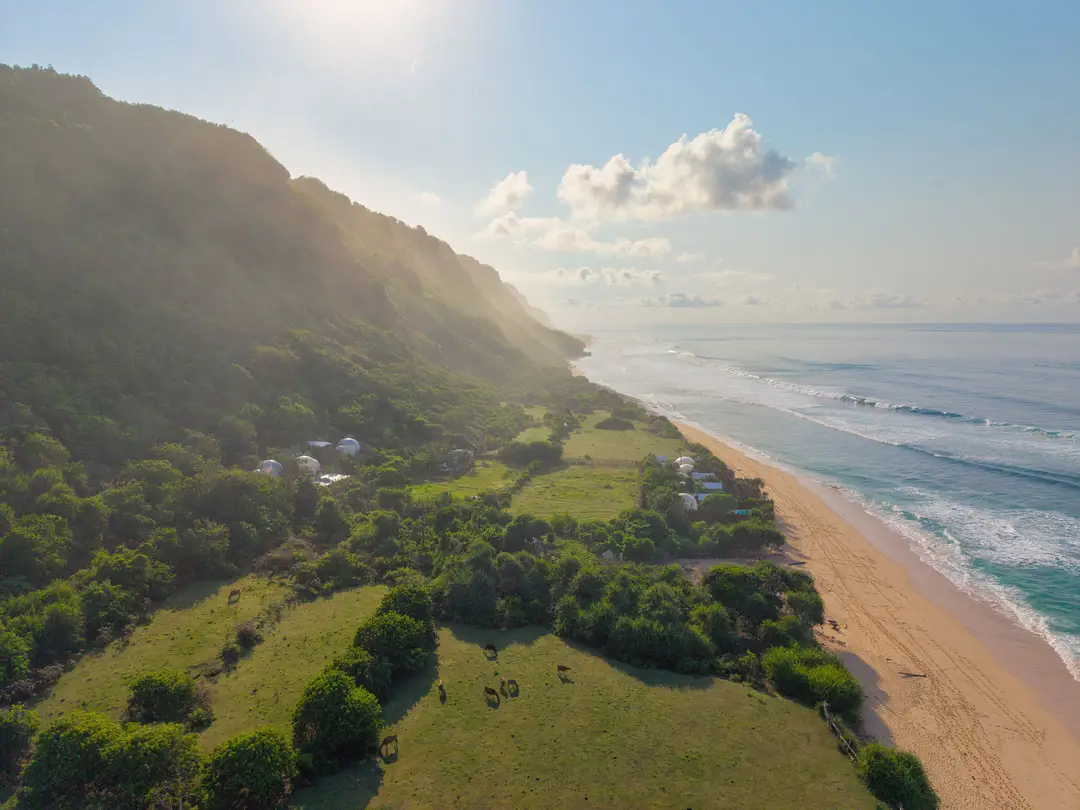 Vue aérienne de la plage de Green Bowl Beach bordée par une falaise verdoyante et l'océan à Bali