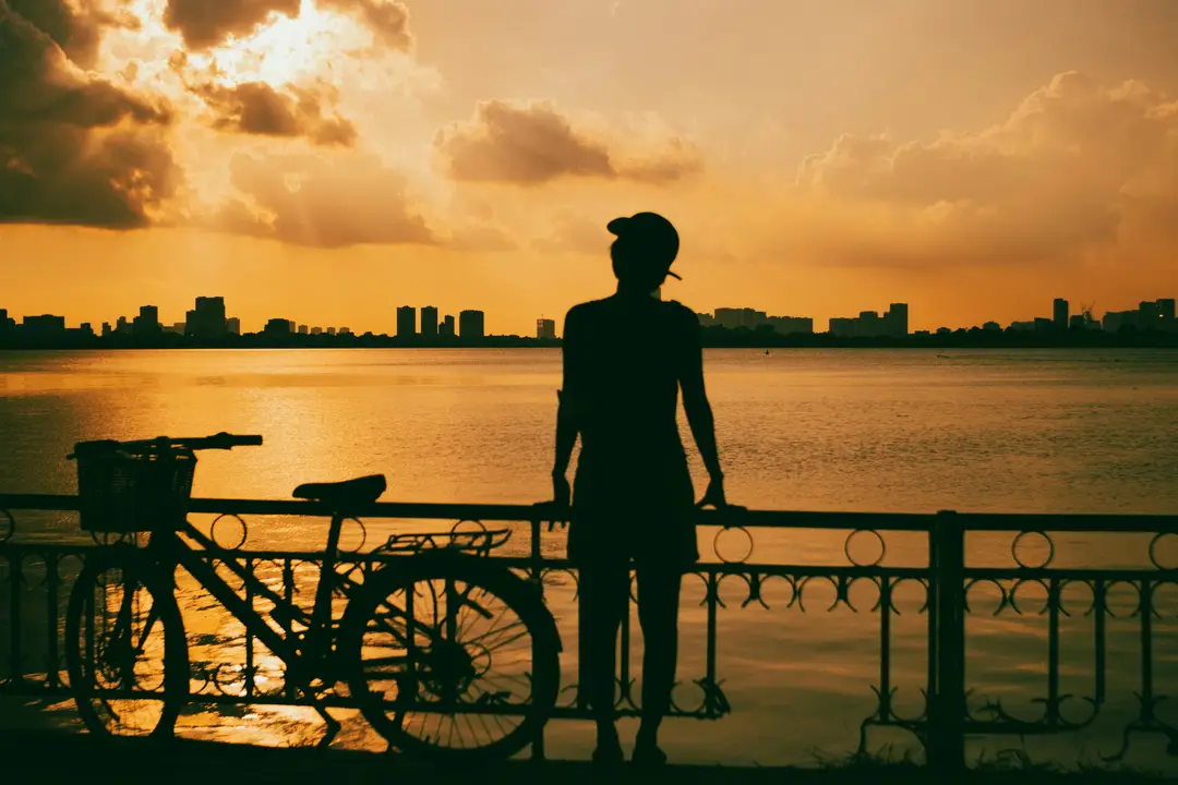 Voyage au Vietnam — cycliste au coucher de soleil au bord d’un lac urbain, découverte du Vietnam à vélo entre ville et nature