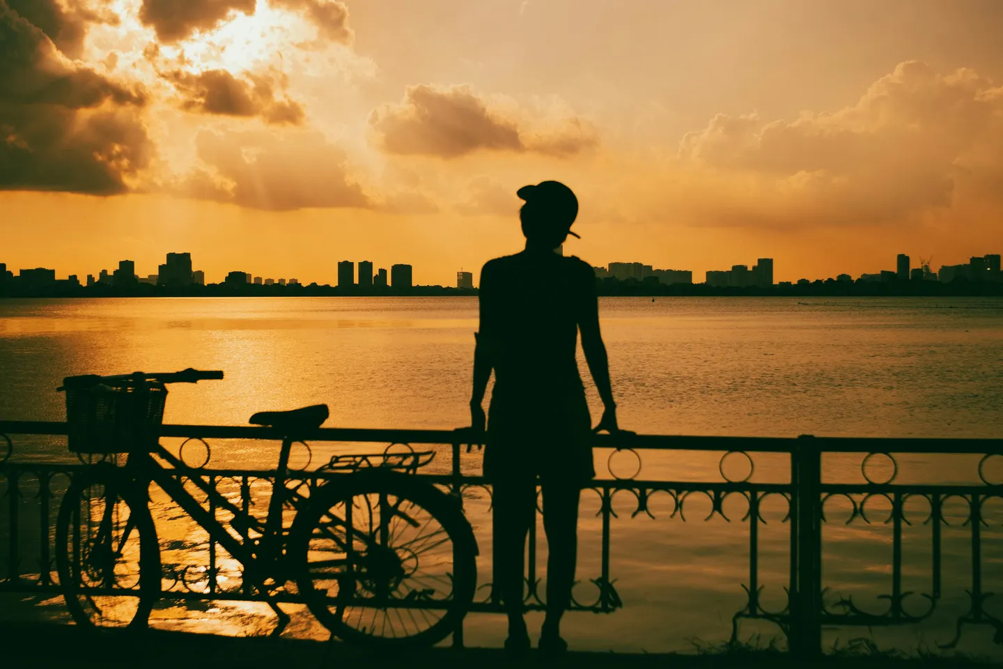 Voyage au Vietnam — cycliste au coucher de soleil au bord d’un lac urbain, découverte du Vietnam à vélo entre ville et nature