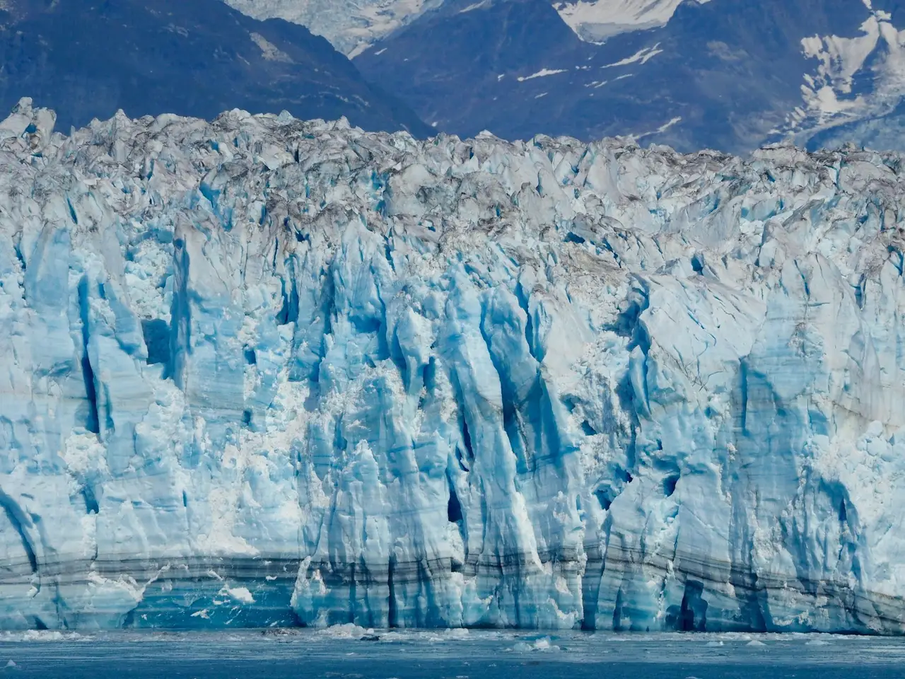 Imposant mur de glace bleutée et crevasses d'un glacier côtier surplombé par des crêtes rocheuses entre Glacier View et Seward en Alaska