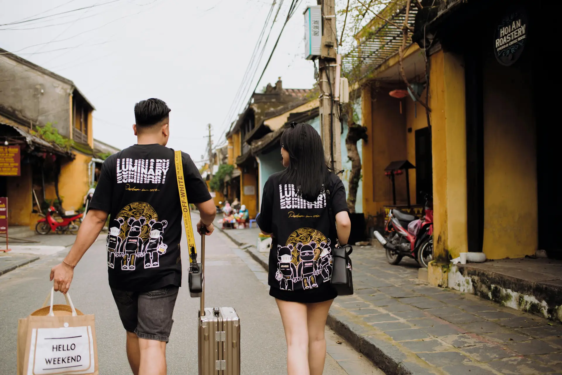 Deux voyageurs marchant avec leurs bagages dans une rue pittoresque de Hoi An au Vietnam.
