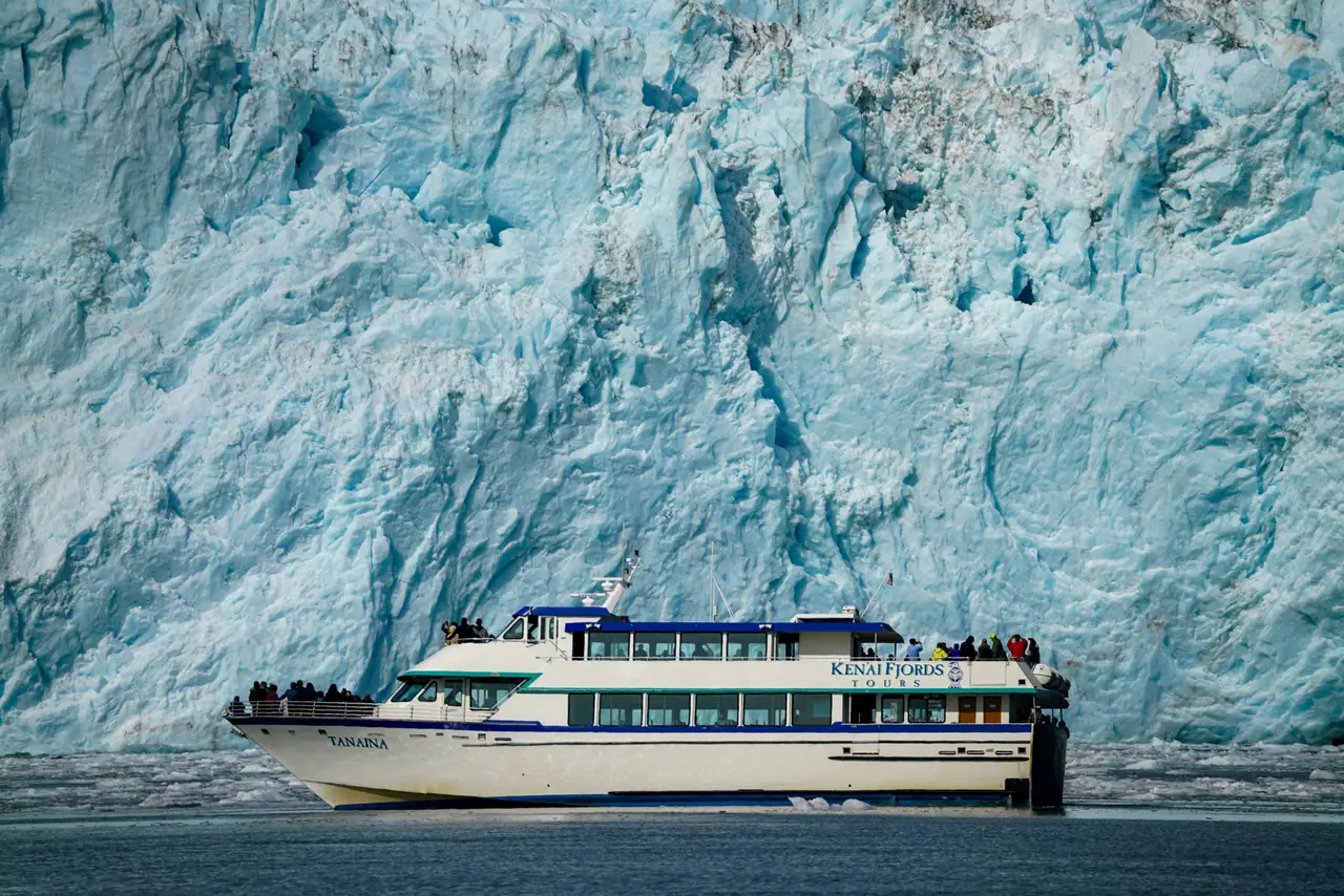 Bateau d'excursion naviguant au pied de l'immense mur de glace bleutée d'un glacier côtier à Seward en Alaska
