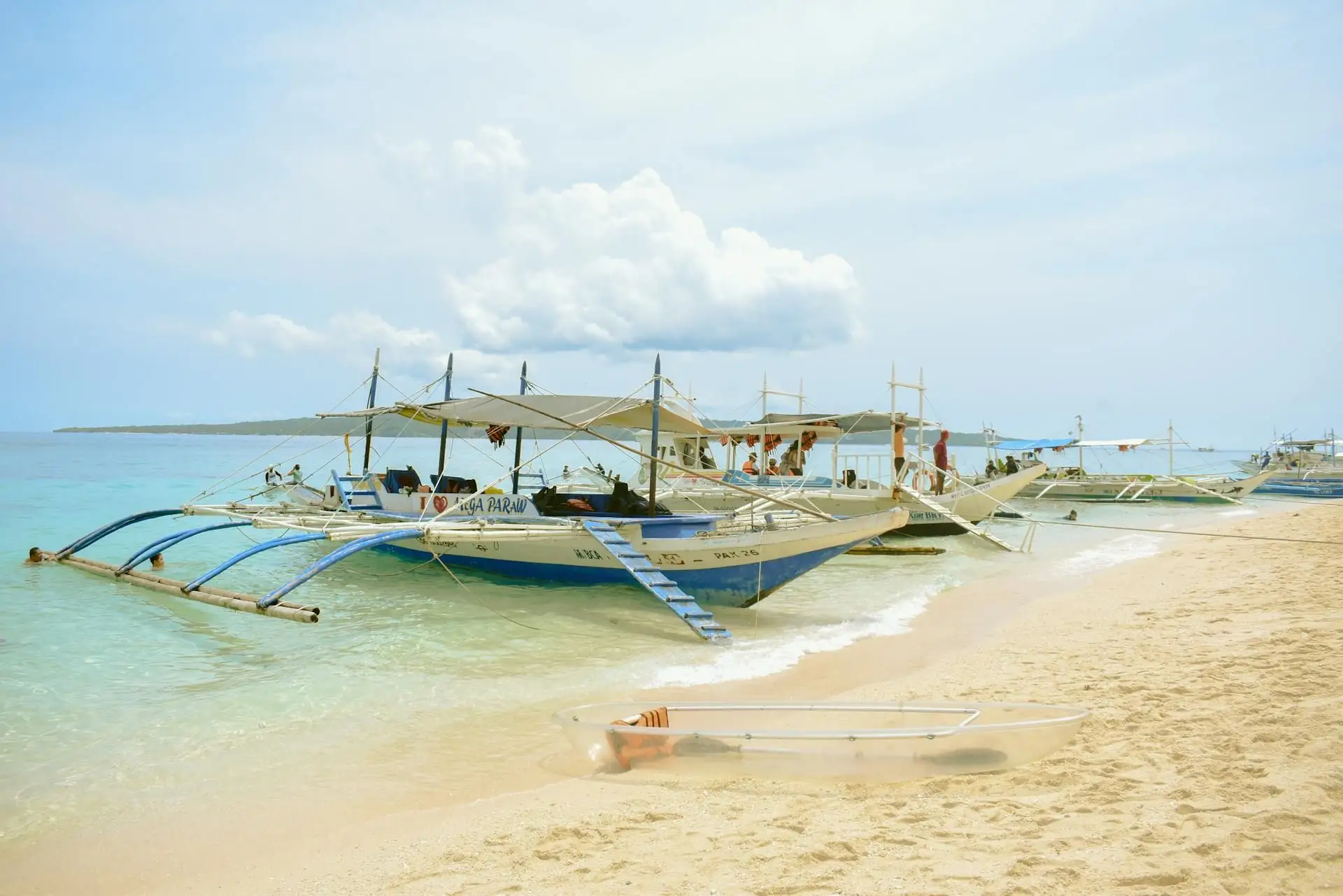 Travel in the Philippines — Traditional Filipino outrigger bangka boats anchored in the clear turquoise waters and white sand beach of Boracay.