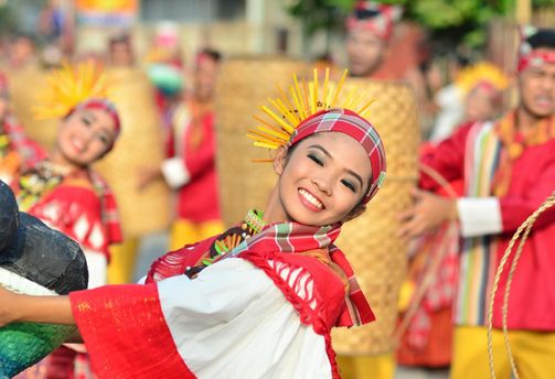 Travel in the Philippines — Smiling female cultural dancer wearing vibrant traditional festival attire during a lively local fiesta celebration in Luzon.