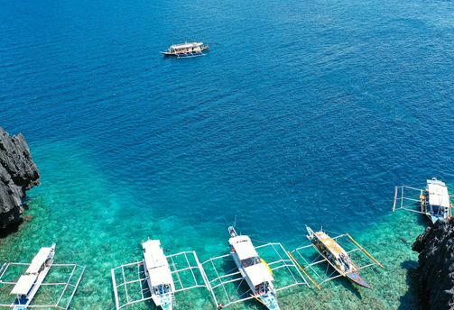 Travel in the Philippines — Several traditional Bangka boats anchored in the clear turquoise waters along the shores of Palawan