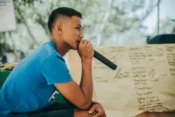 Un homme philippin chantant au karaoké devant une affiche manuscrite lors d'un voyage authentique aux Visayas.