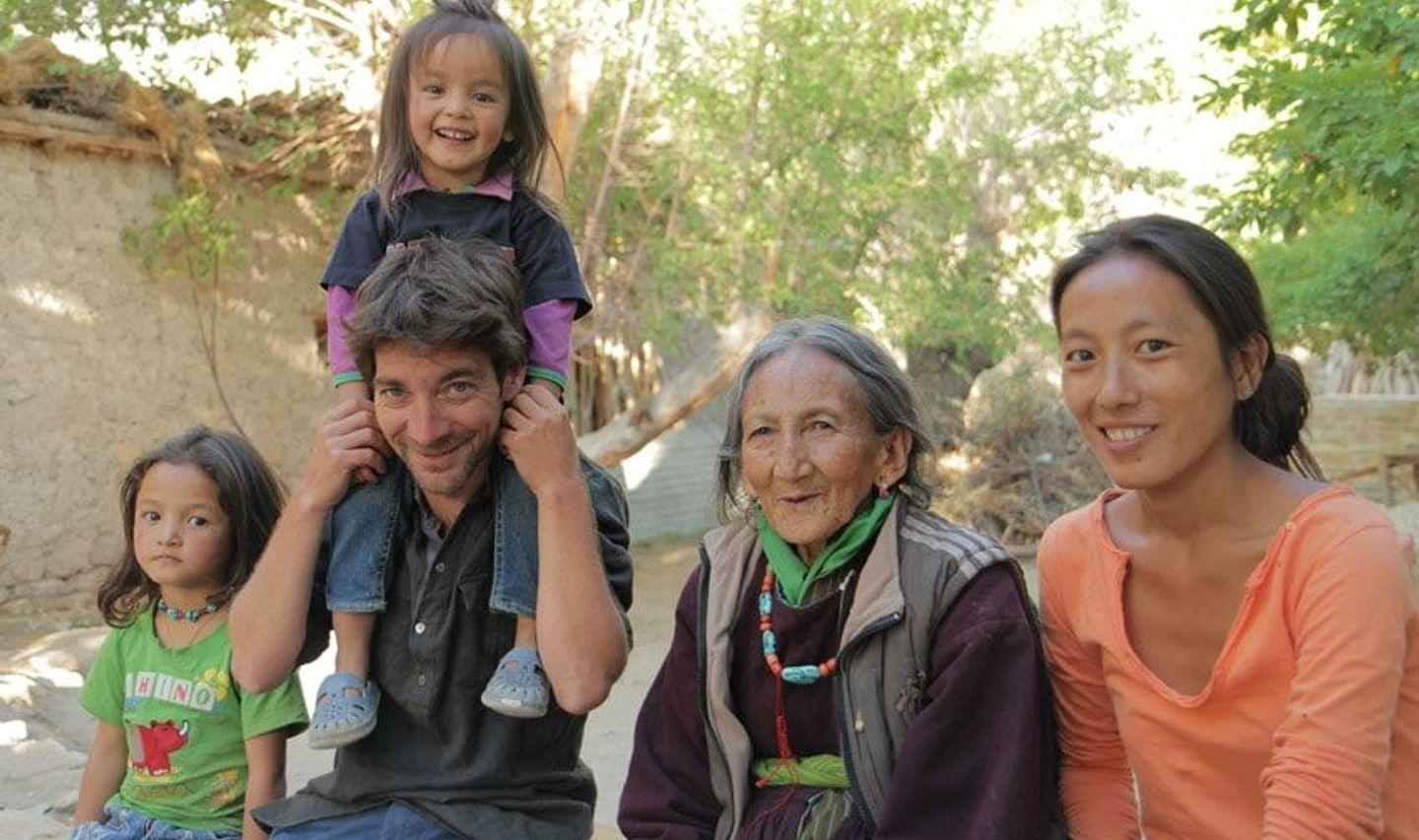 Travel in Asia - Group of people sitting outdoors, smiling together, with a child sitting on an adult’s shoulders