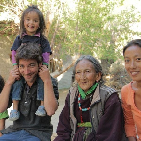 Travel in Asia - Group of people sitting outdoors, smiling together, with a child sitting on an adult’s shoulders