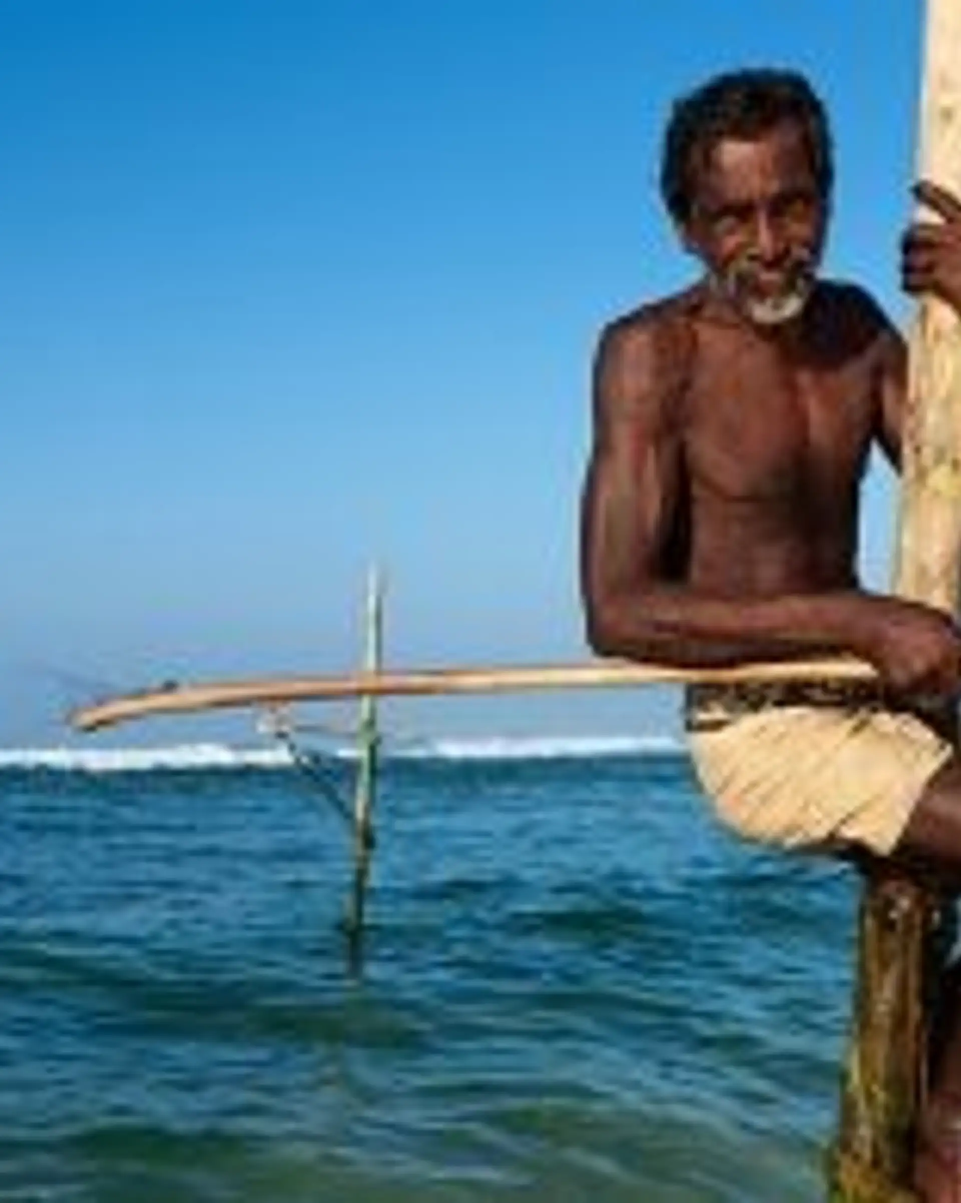 Travel in Asia - A man stilt fishing on a beach in Sri Lanka