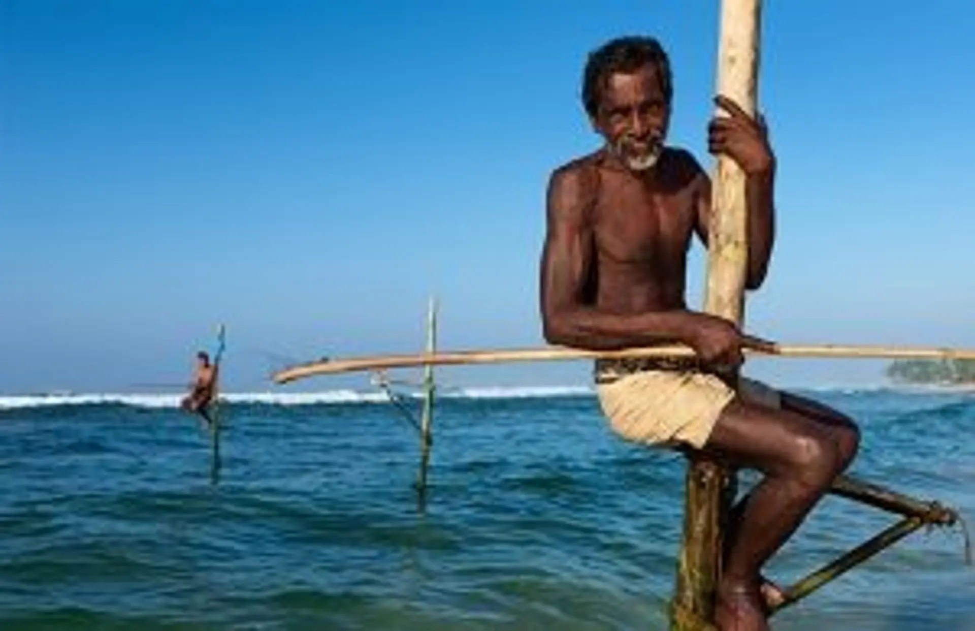 Travel in Asia - A man stilt fishing on a beach in Sri Lanka