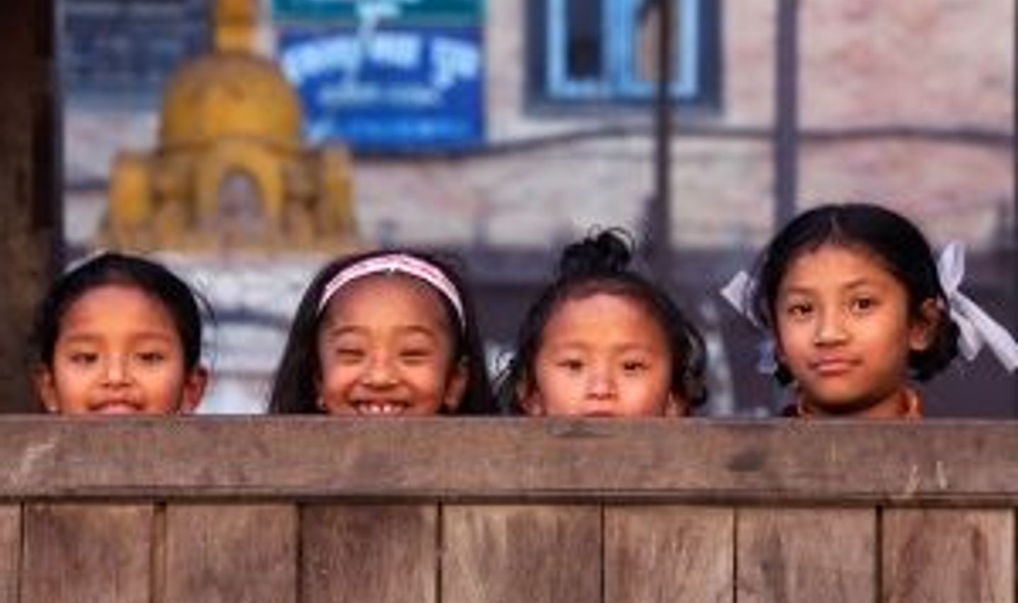 Travel in Asia - Four young smiling Nepalese girls playing hide and seek with the camera