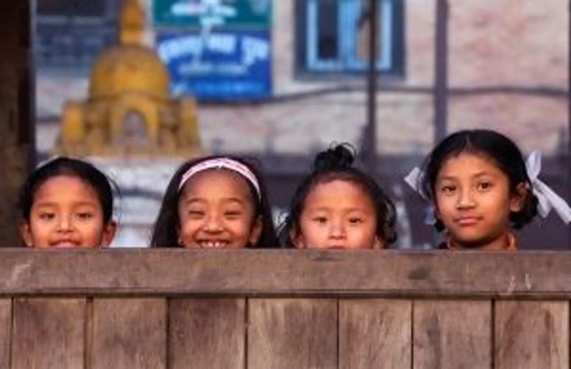 Travel in Asia - Four young smiling Nepalese girls playing hide and seek with the camera