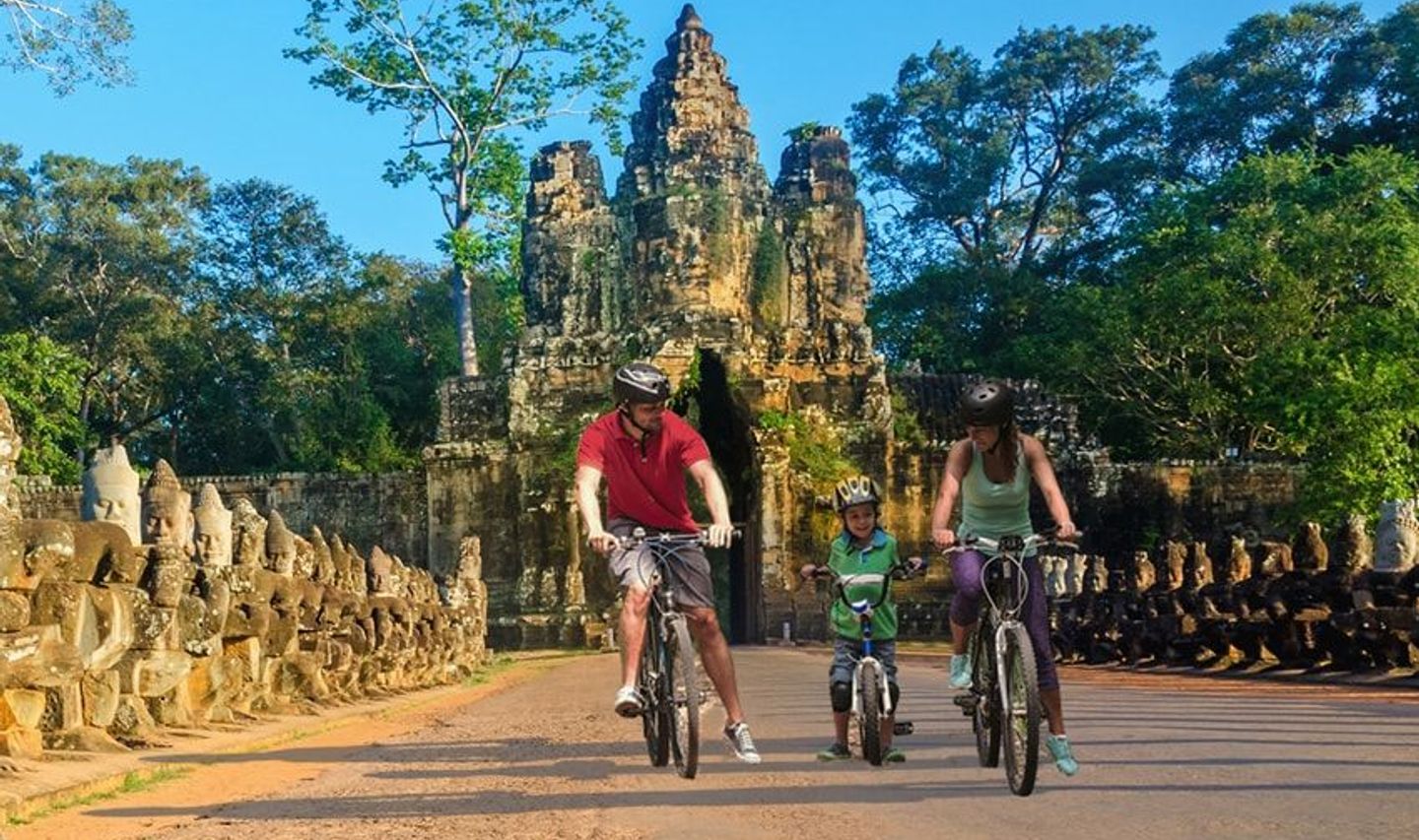 Travel in Asia - Happy family exploring Khmer temples of Angkor Wat by bicycle in Cambodia