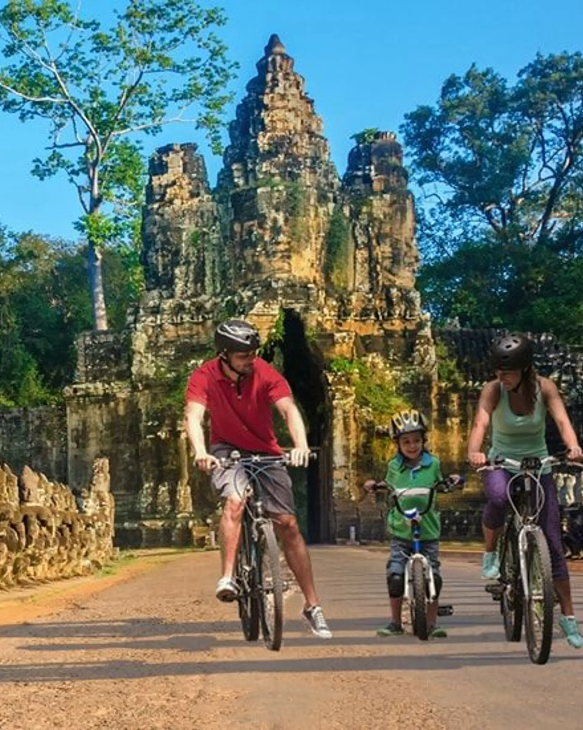 Travel in Asia - Happy family exploring Khmer temples of Angkor Wat by bicycle in Cambodia