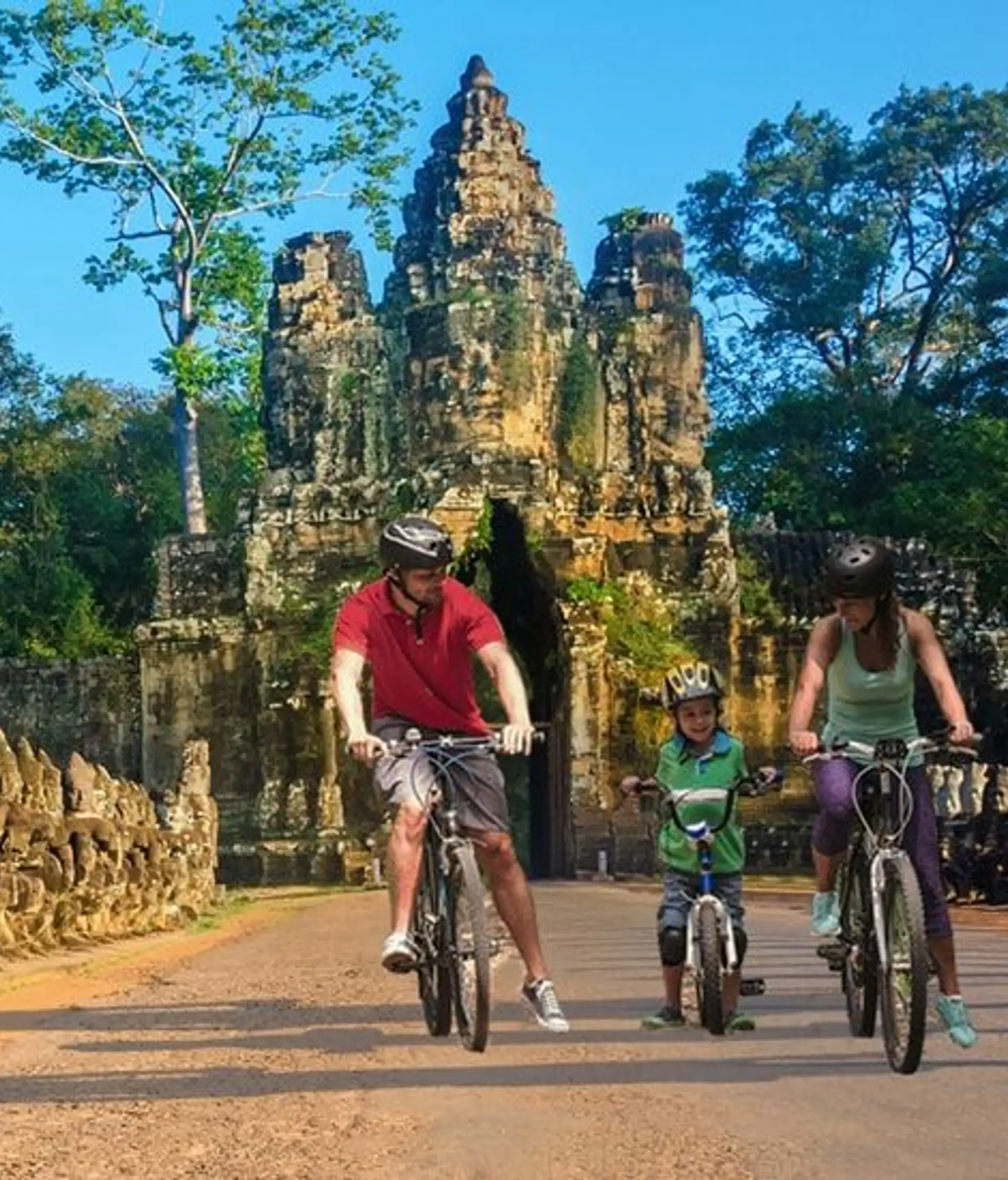 Travel in Asia - Happy family exploring Khmer temples of Angkor Wat by bicycle in Cambodia