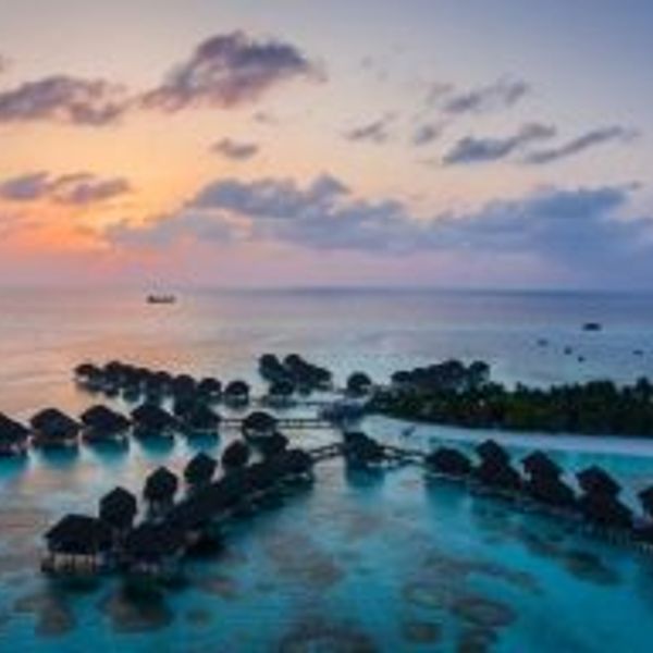 Travel in Asia - Rows of luxury bungalows built on stilts above the clear light blue ocean water of the Maldives