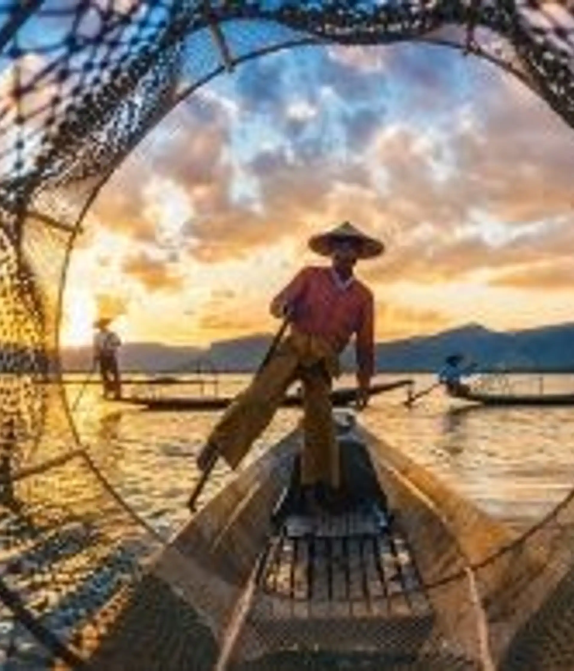 Travel in Asia - Fisherman standing on a wooden boat at sunset, surrounded by fishing nets on calm water