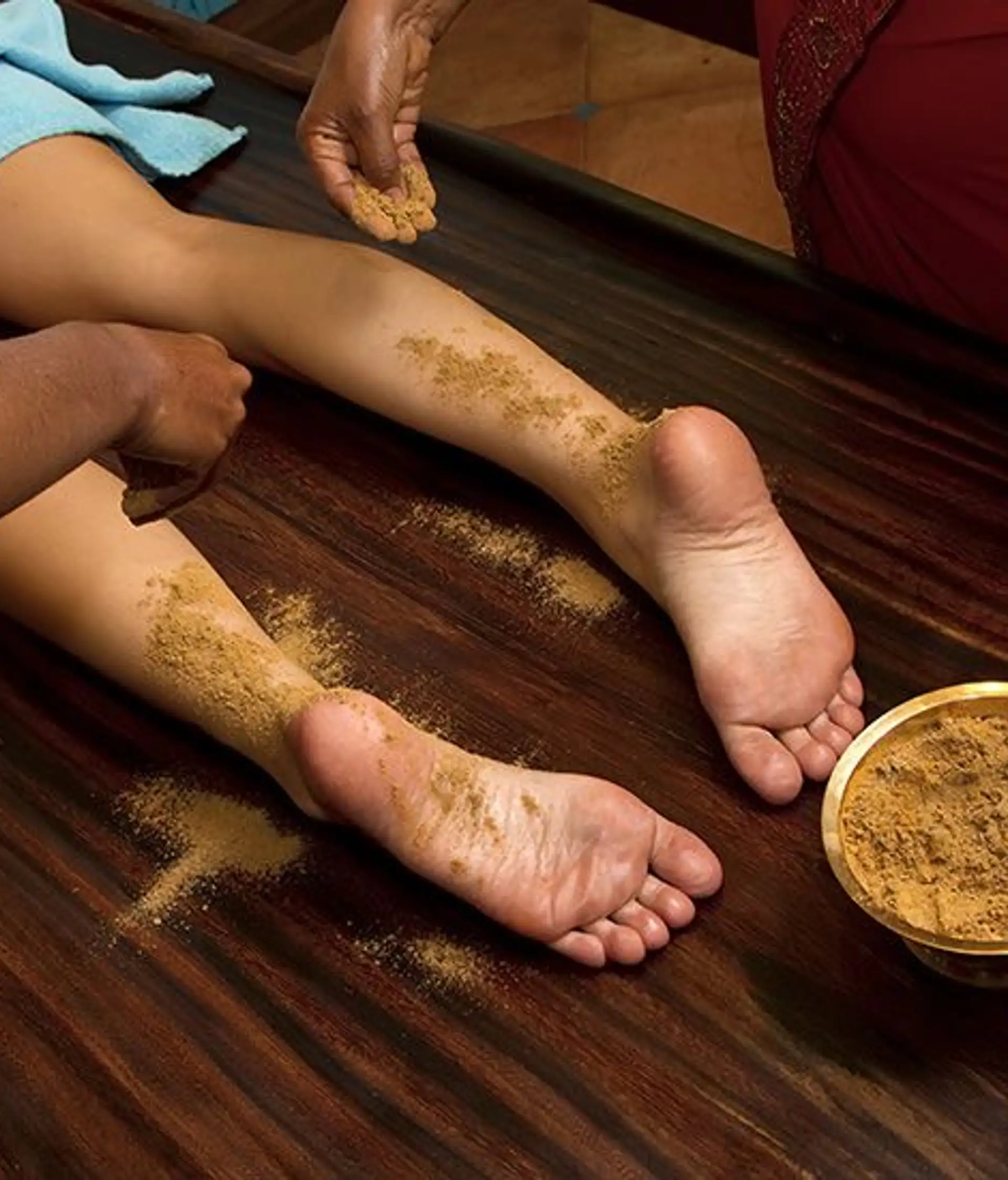 Travel in Asia - Person resting with herbal paste applied to their feet during an Ayurvedic treatment known as Udvartana, with small bowls of natural ingredients nearby