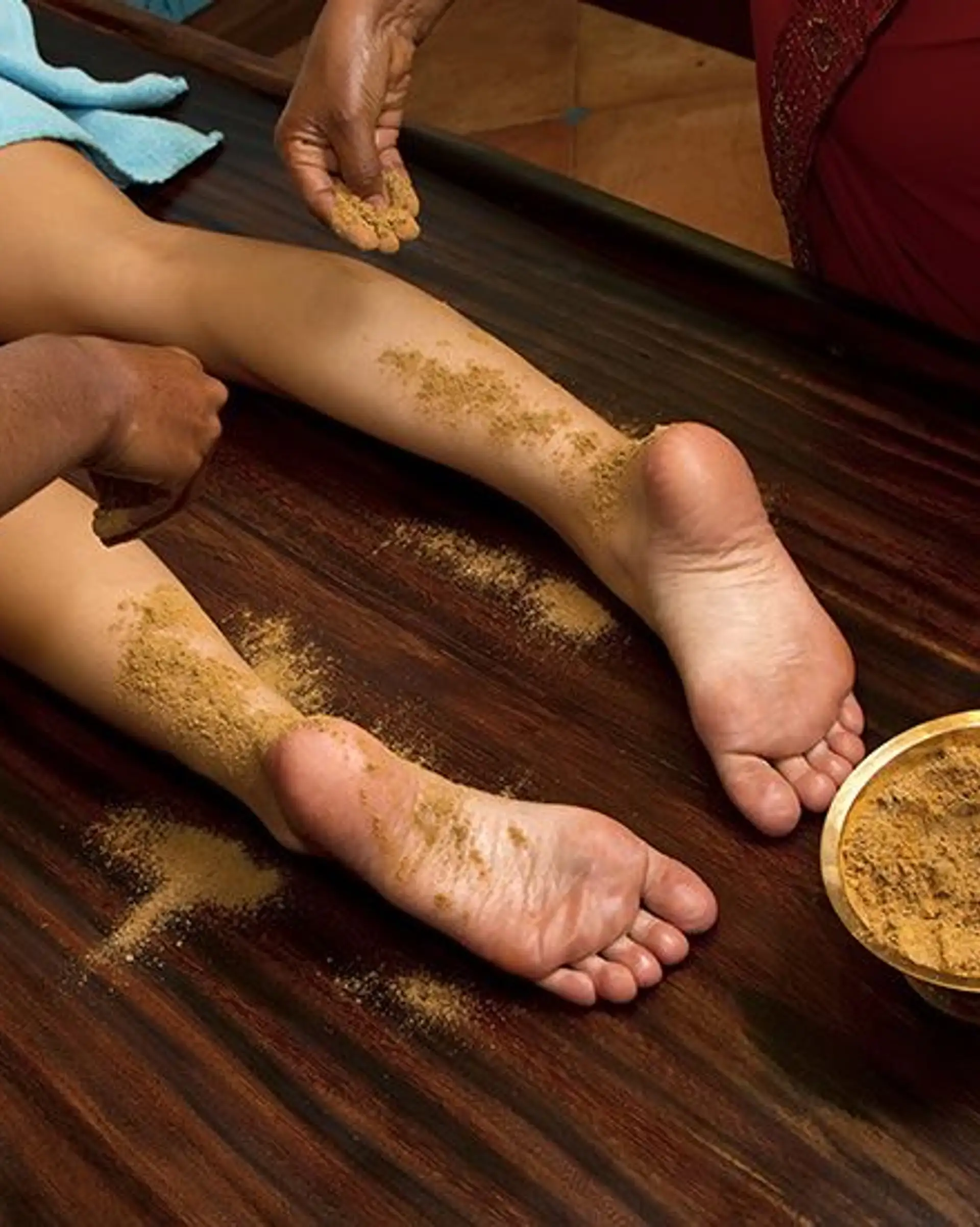 Travel in Asia - Person resting with herbal paste applied to their feet during an Ayurvedic treatment known as Udvartana, with small bowls of natural ingredients nearby