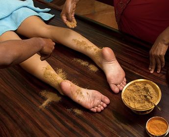 Travel in Asia - Person resting with herbal paste applied to their feet during an Ayurvedic treatment known as Udvartana, with small bowls of natural ingredients nearby