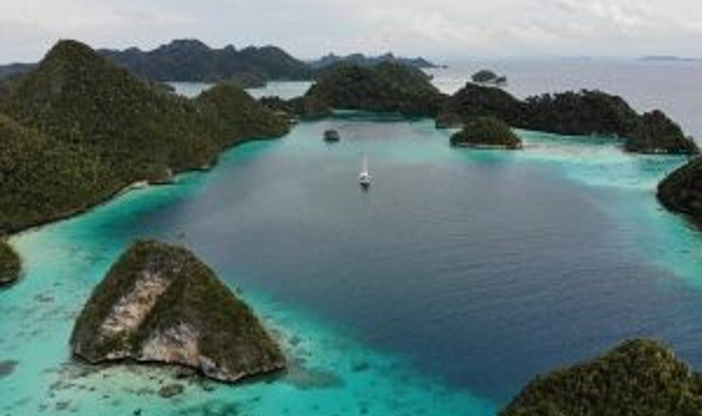 Travel in Asia - Aerial view of turquoise waters surrounding small green islands in the Raja Ampat archipelago, Indonesia