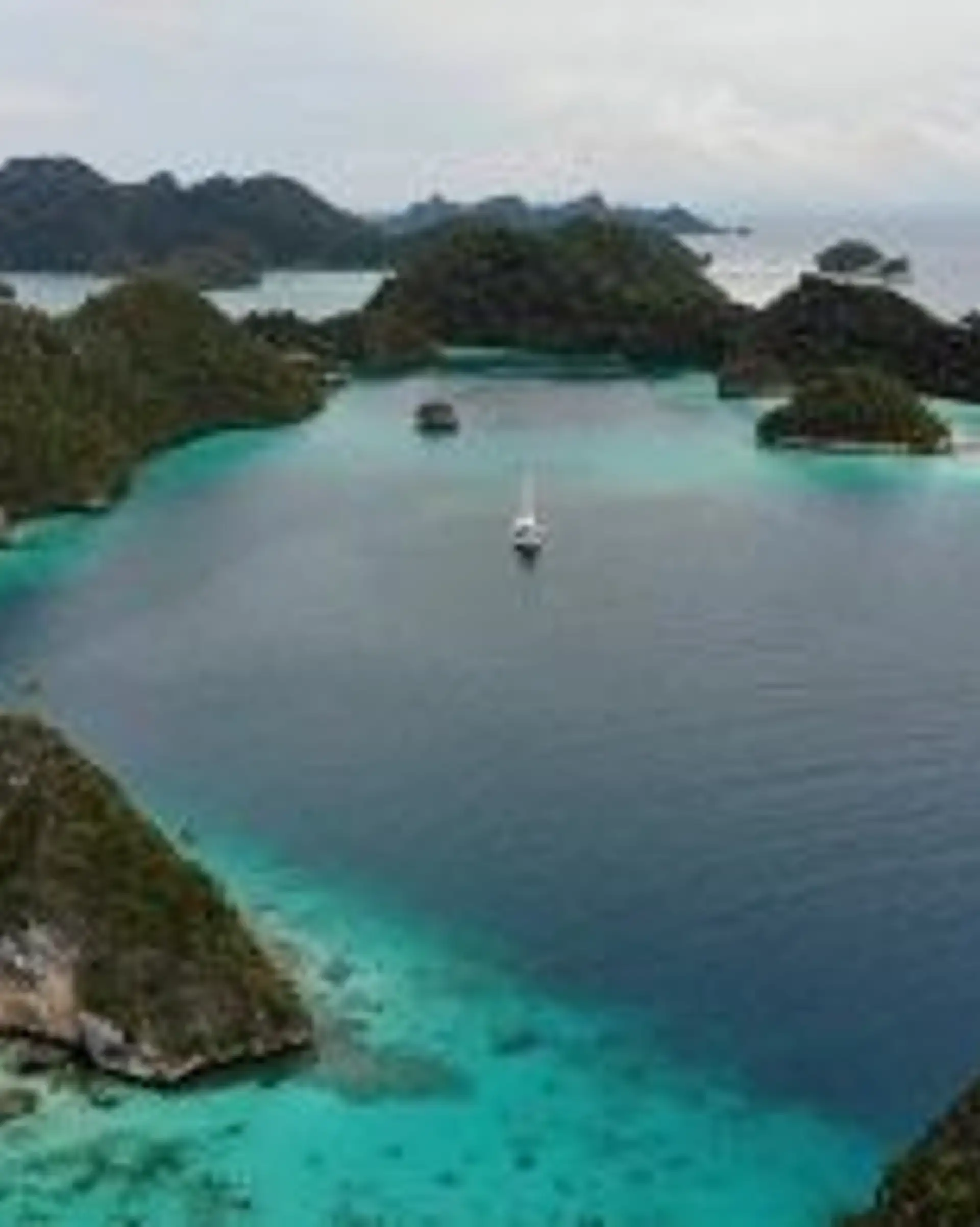 Travel in Asia - Aerial view of turquoise waters surrounding small green islands in the Raja Ampat archipelago, Indonesia