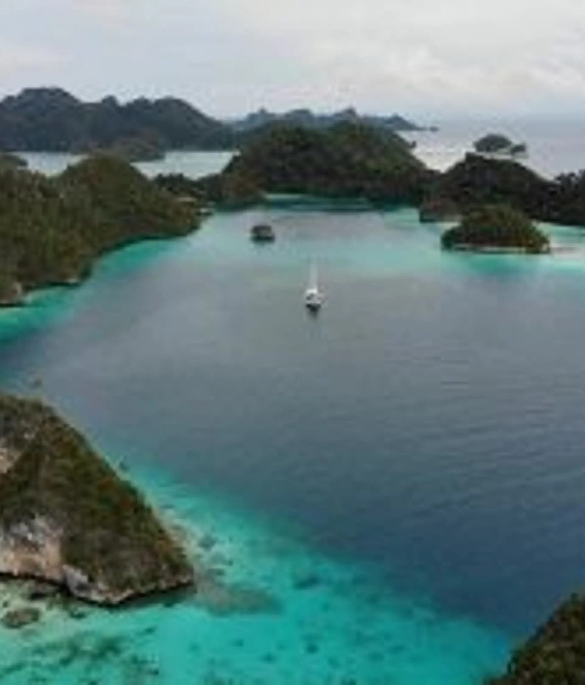 Travel in Asia - Aerial view of turquoise waters surrounding small green islands in the Raja Ampat archipelago, Indonesia