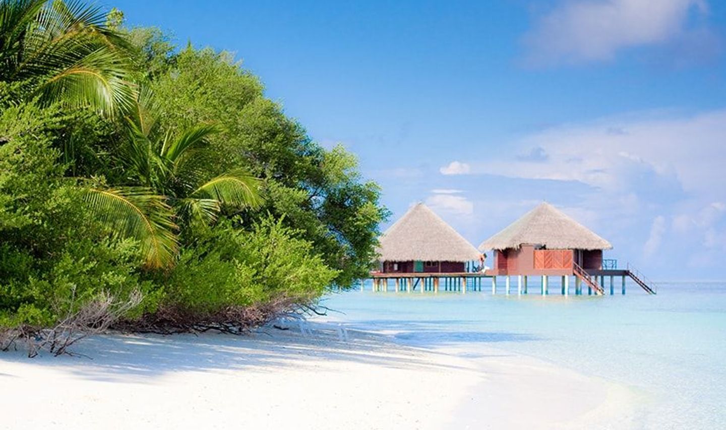 Travel in Asia - Two overwater villas on a white-sand beach on a clear, sunny day in the Maldives