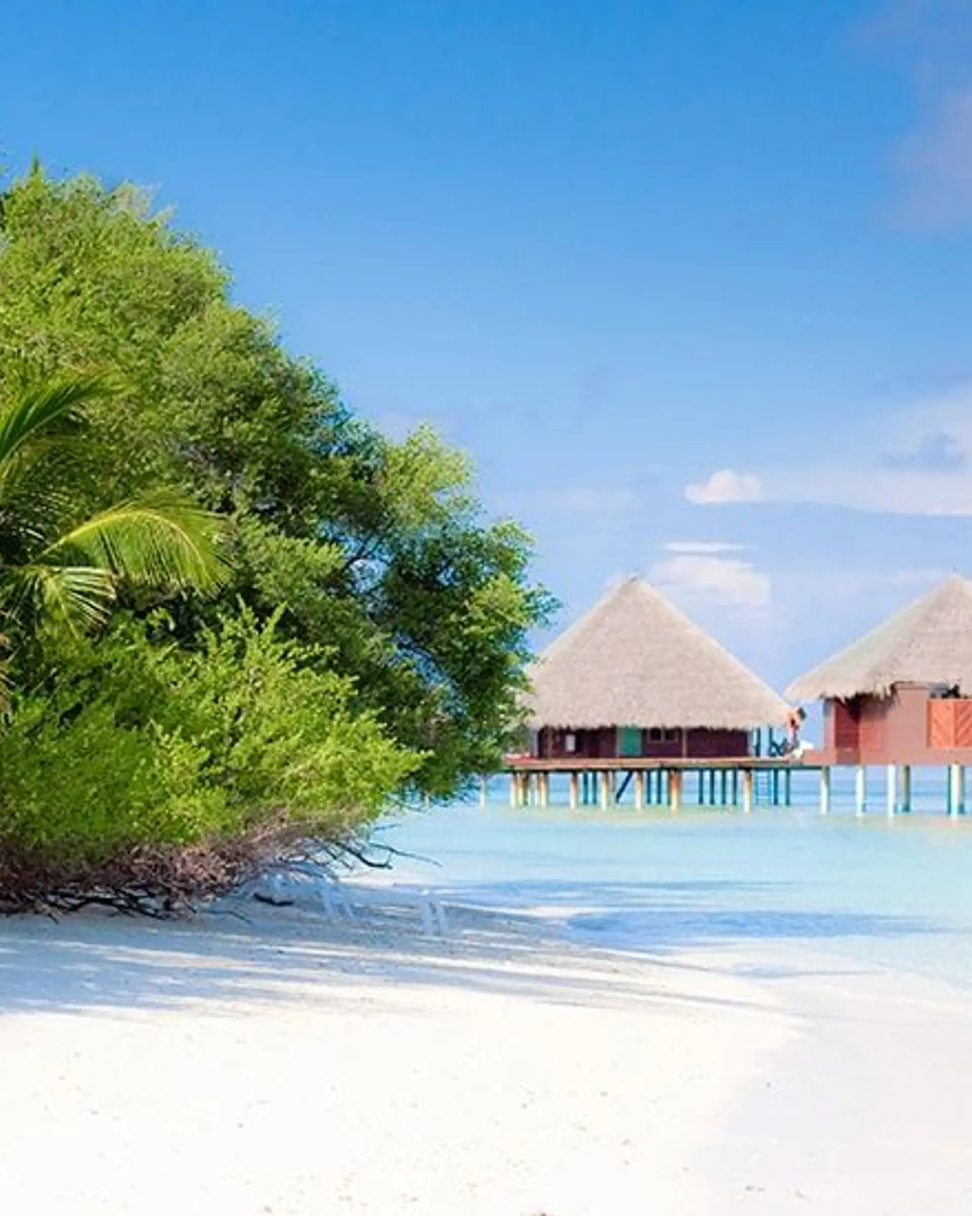 Travel in Asia - Two overwater villas on a white-sand beach on a clear, sunny day in the Maldives